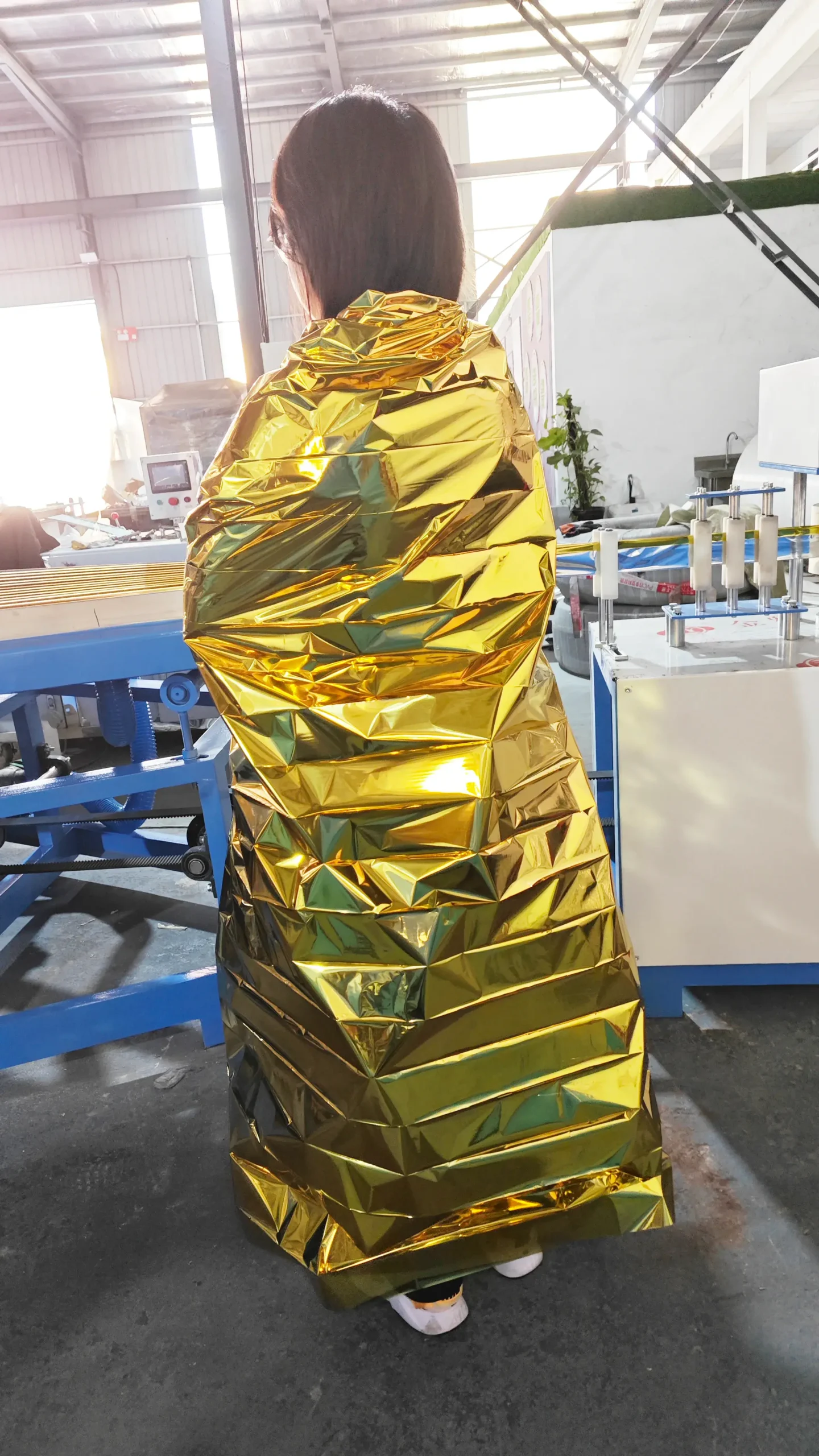 A person wearing a finished emergency blanket made from ZXJ Machinery's folding system, demonstrating the blanket's functionality and lightweight design.