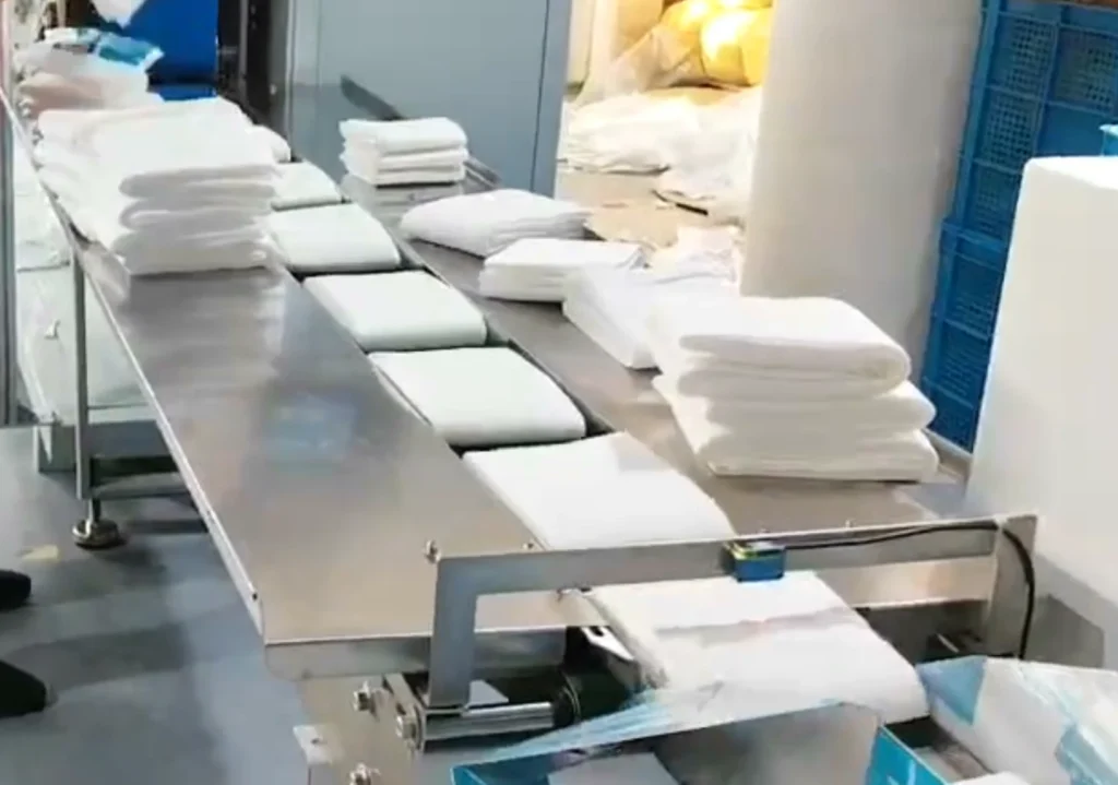 Manual arranging of disposable towels and feeding into packaging equipment on the production line.
