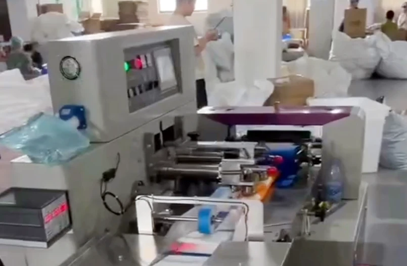 Disposable bath towels being packaged in a pillow-style back-seal packaging machine.