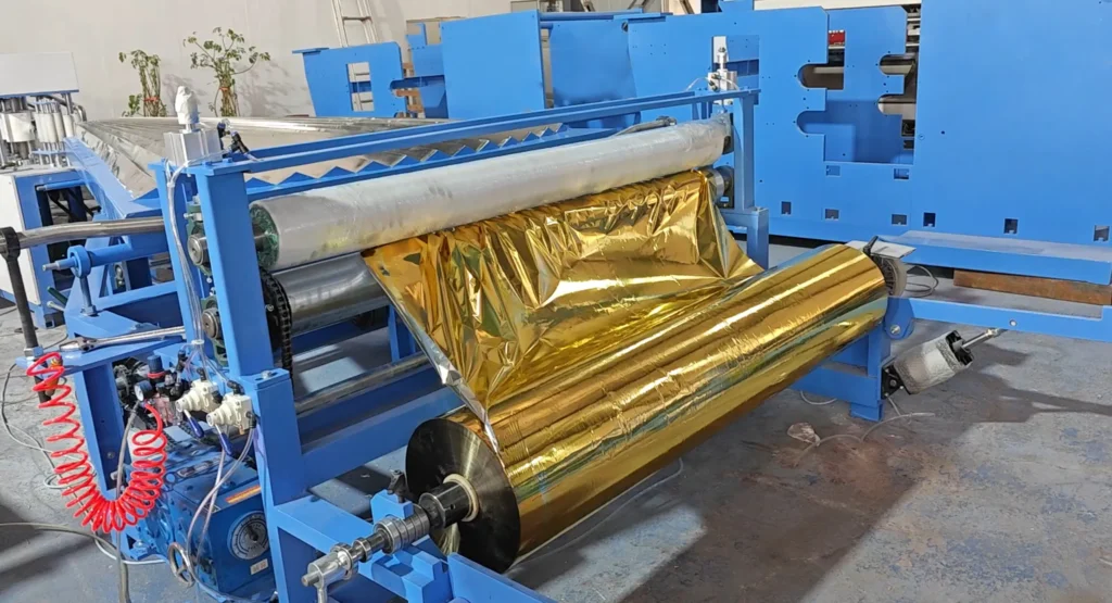 Vacuum aluminized film raw material roll installed on the tailstock of ZXJ emergency blanket folding machine, ready for production.